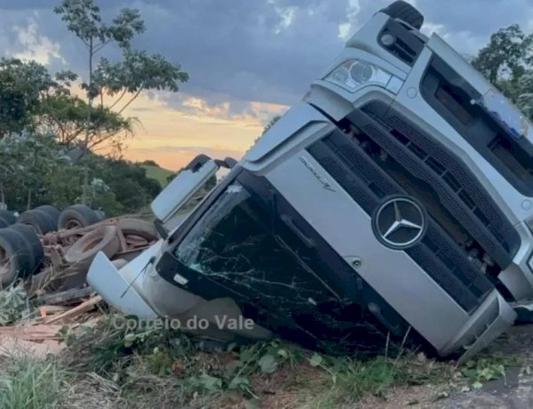 Caminhão com carga de madeira capota e fica com rodas para cima na RO-473