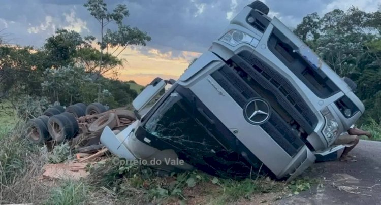 Caminhão com carga de madeira capota e fica com rodas para cima na RO-473